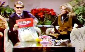 Vintage scene with a man holding a bag of 'Famous' brand product in a living room setting.