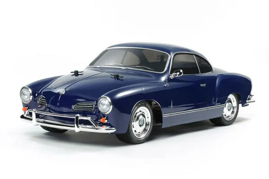 A blue Tamiya 1/10 scale model of a VW Karmann Ghia on a white background, unassembled kit with motor and ESC.
