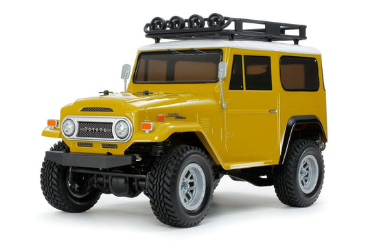 Tamiya 1/10 scale RC Toyota Land Cruiser 40 CC-02 Chassis assembly kit displayed unassembled with yellow body and silver wheels.